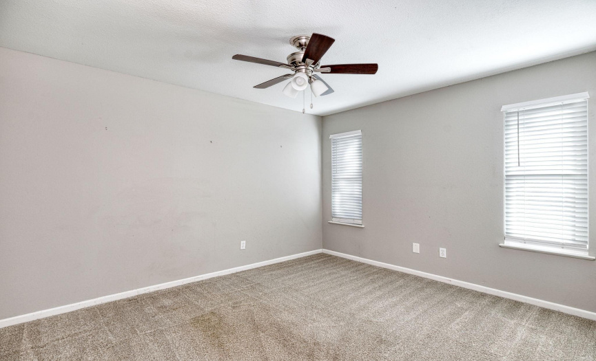 The secondary bedroom has a ceiling fan, carpet throughout and two windows that allow for natural light. 