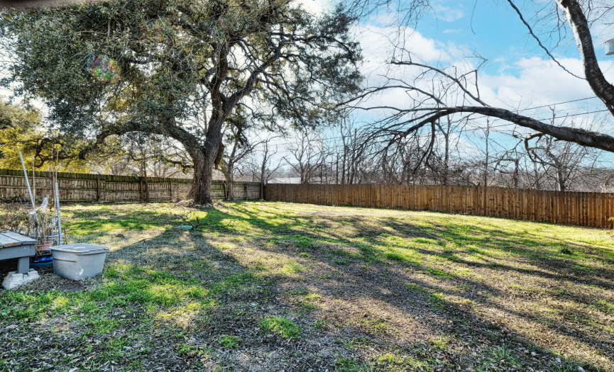 The large backyard has mature trees, and a privacy fence all around. 