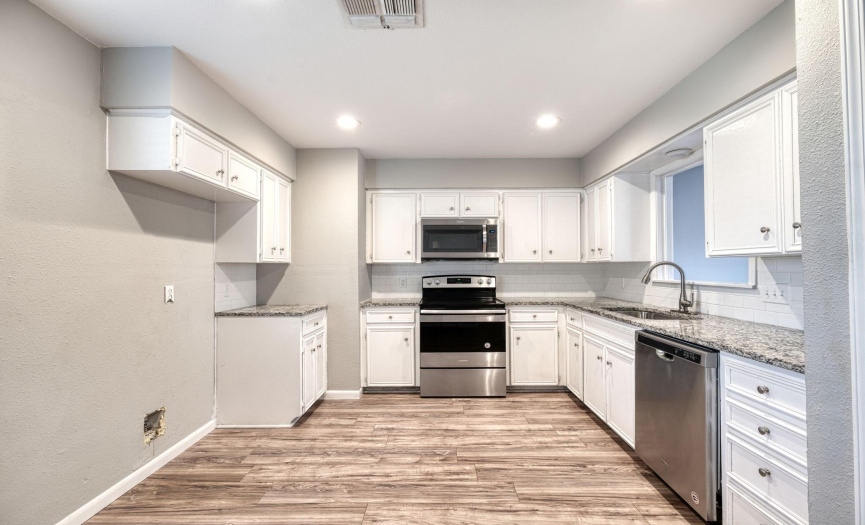 The kitchen has recessed lighting with stainless steel appliances, granite countertops. 