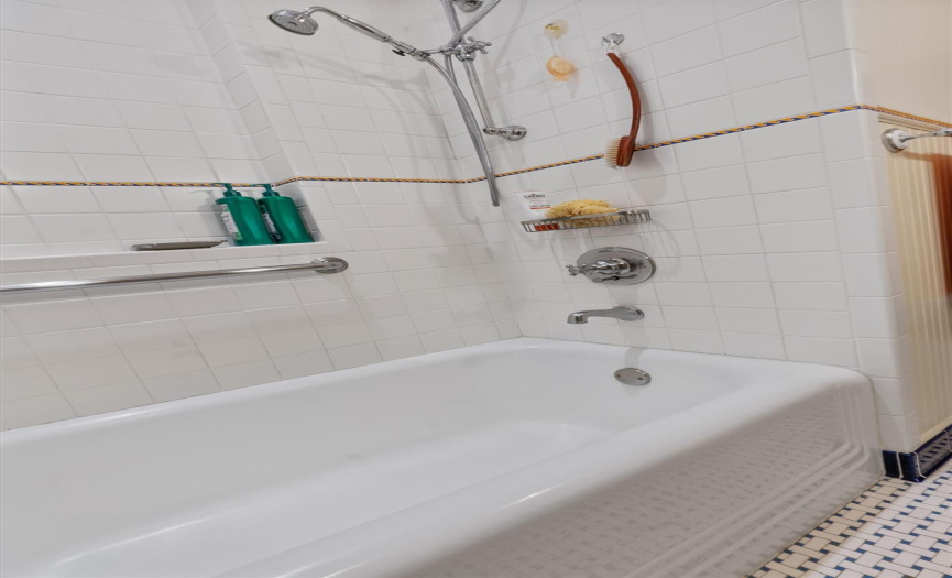 Original tub with updated floor to ceiling tile walls, feature strip & shower niche