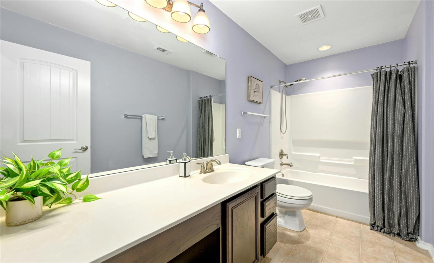 This spacious secondary bathroom provides a sizable single vanity with dressing table seating and a shower/tub combo. 