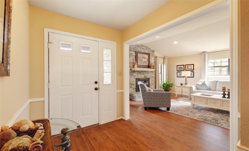 Entry door with sidelight and foyer open to living area. Chair railing and wood trim over entry to living looks nice.