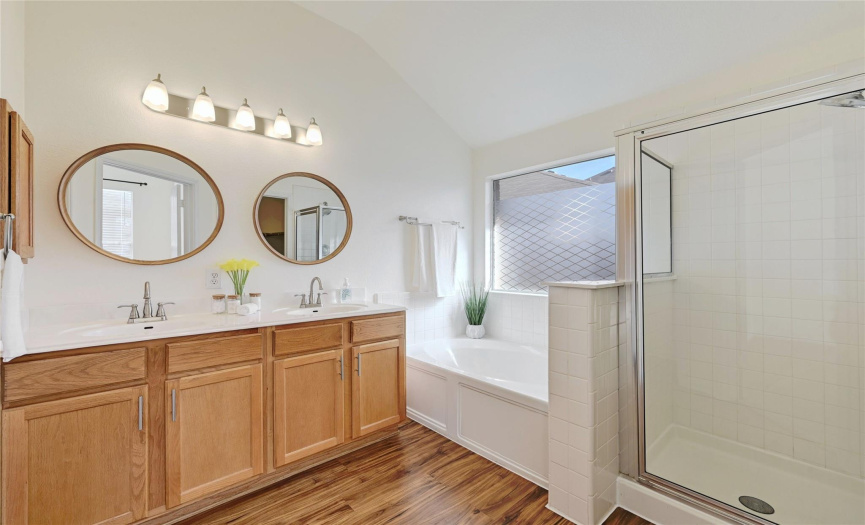 Double doors in the primary suite open into your private ensuite bath with dual vanity, stylish mirrors, updated luxury vinyl plank flooring, garden tub, shower, walk-in closet, and private commode. 