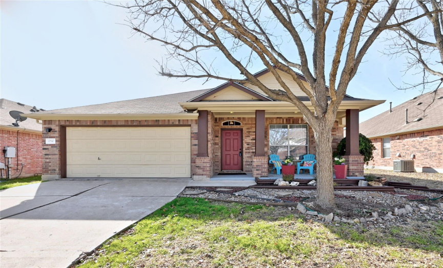 Lovely curb appeal with delightful mature landscaping, shade tree, a covered front porch, brick masonry, and a two-car garage. 