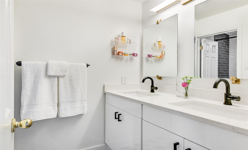 Extensively renovated, the bath for the secondary bedrooms boasts a dual vanity and cabinet storage.