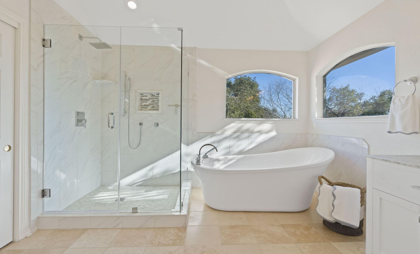 Spacious walk-in shower features sleek frameless glass enclosure.