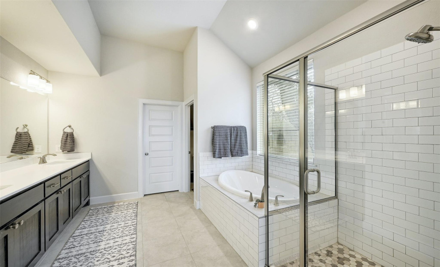 Completing the ensuite bath is a separate shower and soaking tub encased by classy subway tile.