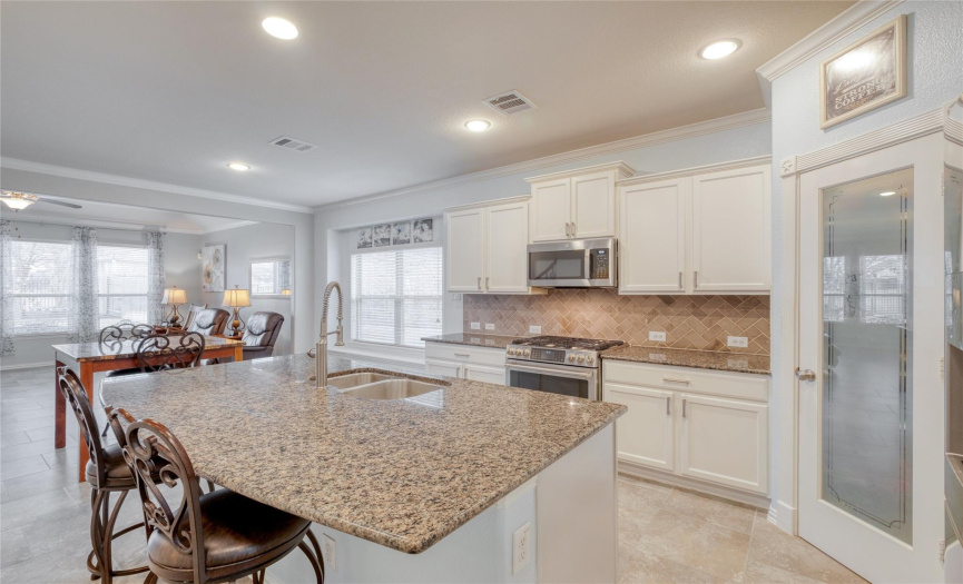 Charming granite countertops, a large center island/breakfast bar combo, and recessed lighting throughout the bright kitchen.