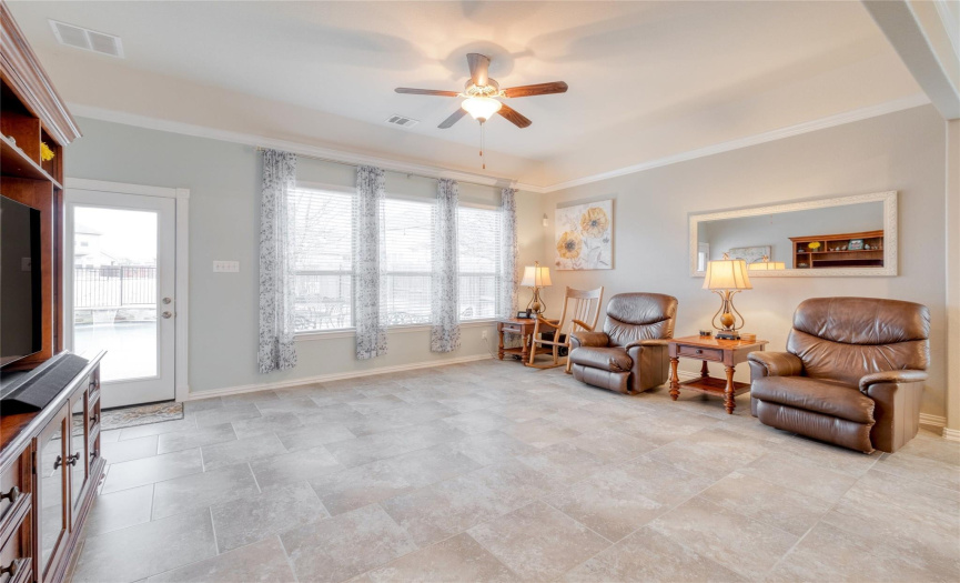 High ceilings, crown molding, and a ceiling fan in the spacious living area.