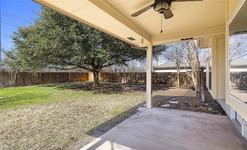 Large backyard with shade trees and covered patio