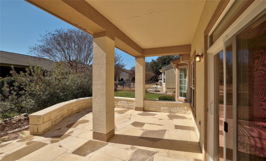 Covered flagstone back patio with limestone seating wall.