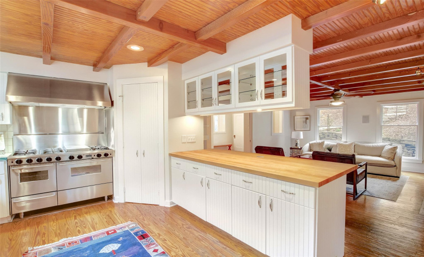 In the kitchen, a variety of glass-front and enclosed cabinets provide flexible storage options to meet your needs, while wood ceiling beams overhead add character.