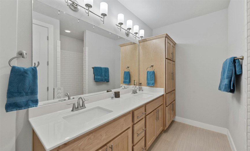 The second floor primary's private ensuite bath provides a spacious dual vanity, designer tile floors and generous cabinetry storage. 