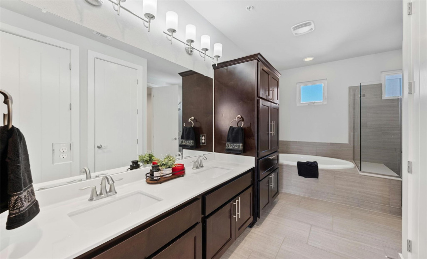 This stunning primary bathroom features a spacious dual vanity with amazing bonus cabinetry storage on both ends, plus stylish tile flooring.