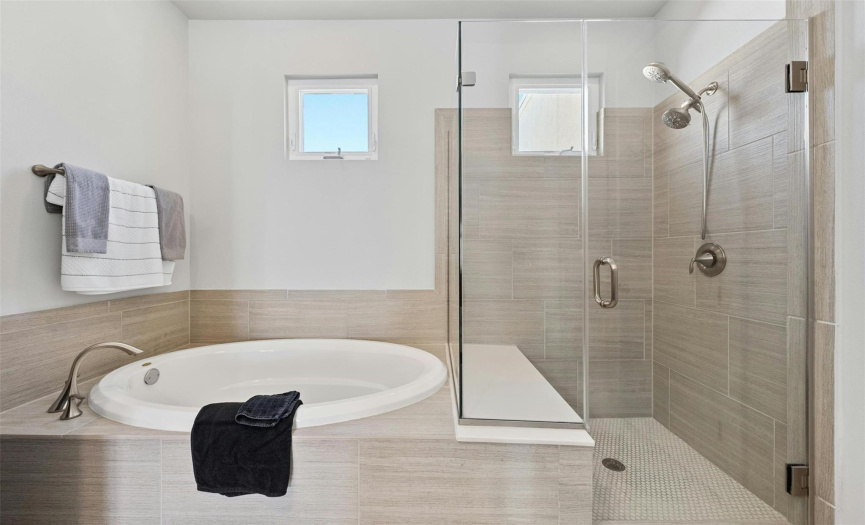Soak off the day's stress in the relaxing built-in garden/soaking tub  in the third floor primary ensuite bath and enjoy an elegant frameless glass walk-in shower, both with gorgeous tile surround.