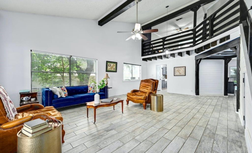 Your eyes are drawn to the unique stylistic details of the dark planks lining the stairway and loft and prominent beams framing the walkway between the home’s two living rooms.