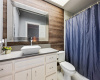 En suite bathroom for lower level bedroom with great storage, tub/shower combo and wood accent wall. 