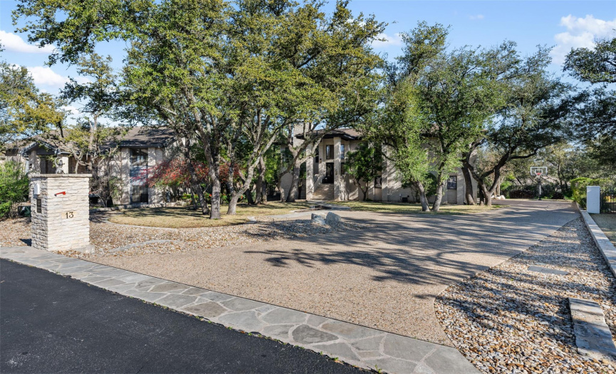 Surrounded by mature Live Oak trees. Long expansive driveway provides more than ample parking. Note the fun basketball goal at the end of the driveway. 