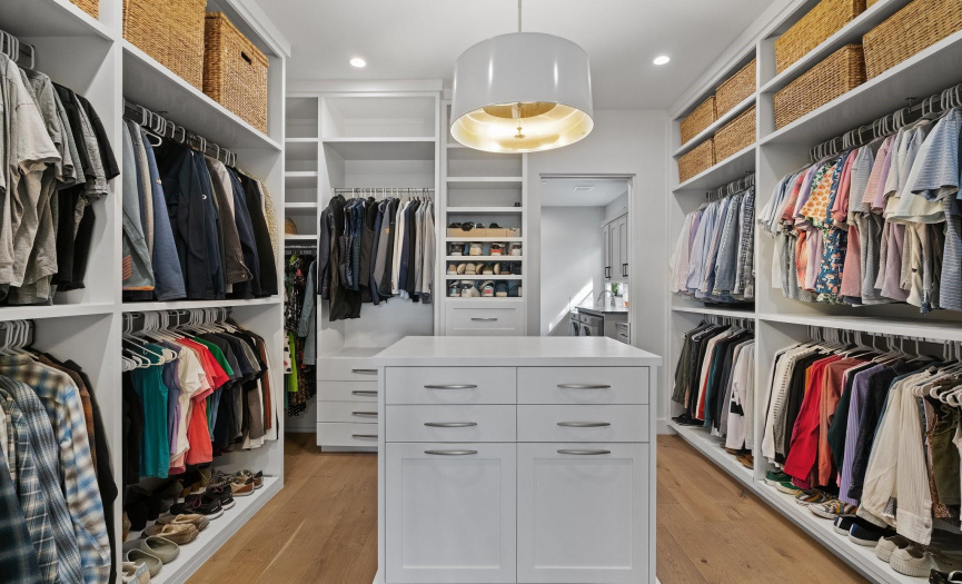 Custom primary closet includes pull out shoe racks.
