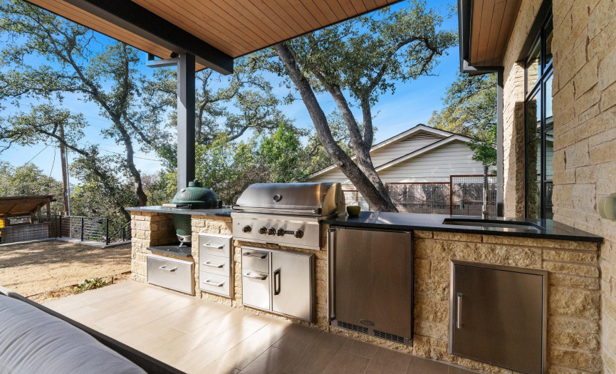 Outdoor kitchen includes a sink and refrigerator.