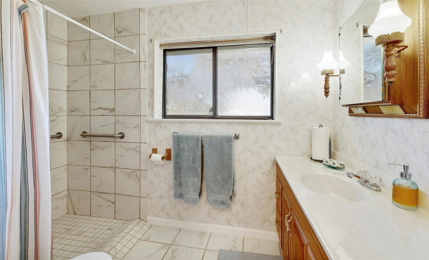 The guest bathroom is equipped with an extended single vanity and a walk-in shower.