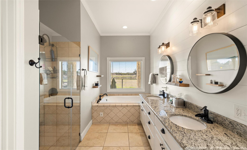 Primary bath has double vanity with granite plus updated paneled wall, light fixtures and mirrors.