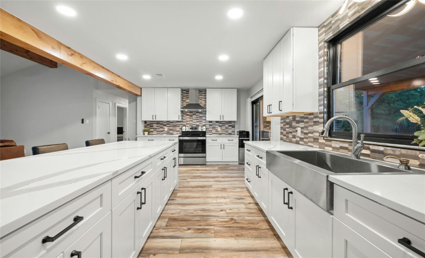 This kitchen has many elegant touches. The kitchen offers shaker style cabinets with tons of storage space, contemporary backsplash, luxurious quartz countertops, LED recessed lighting, stainless steel appliances with modern range vent hood, deep, single basin sink, and cabinet pulls.