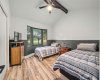 The secondary bedroom has the beautiful wood-looking vinyl flooring, a tall vaulted ceiling with a wood beam, chair railing, a modern ceiling fan and a very nice view of the front yard. The home has a very custom feel.