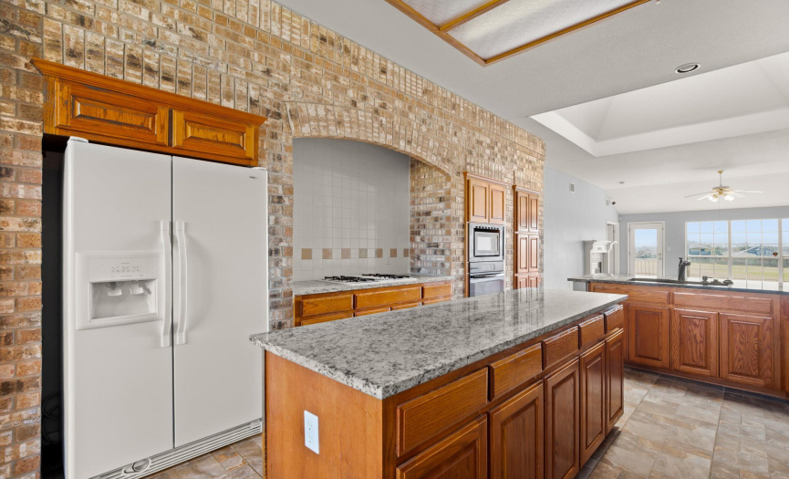 Kitchen with brick accent wall, center island, granite counters