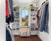 Spacious walk in primary closet has a large window for natural lighting and the ability to get some fresh air as well as custom shelving units.
