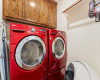 Laundry room has storage cabinetry + shelving and washer/dryer convey