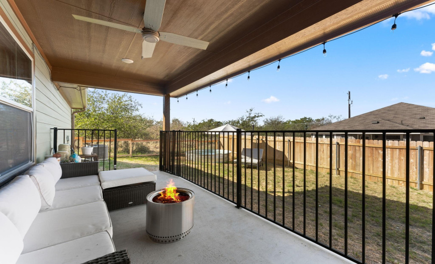 Beautiful covered concrete patio with black metal railing plus string lighting to enjoy when the sun goes down!
