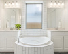 A central soak-in tub surrounded by dual vanities.