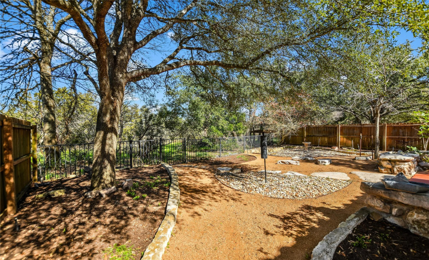 The fenced-in yard is sustainably landscaped with xeriscape, stone pathways, and rock gardens all under the shade of soaring trees.