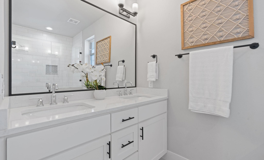The primary ensuite bath boasts an elegant dual vanity with a quartz countertop and timeless Shaker style cabinetry. 