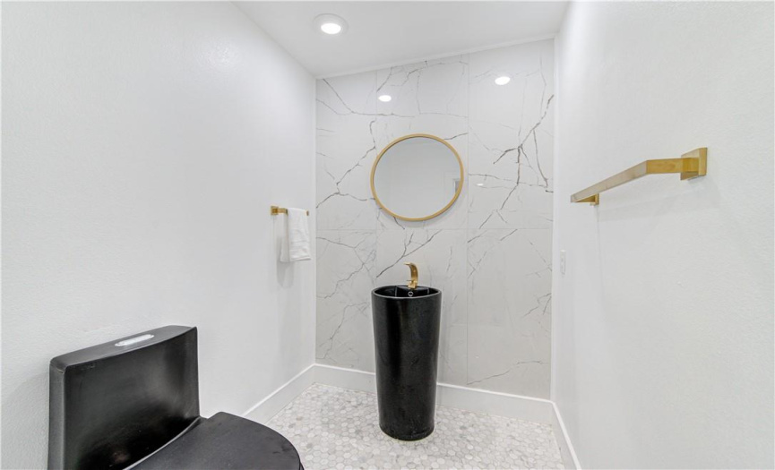 The completely redone artistic guest bathroom includes a modern push-button toilet, vanity, and decorative wall.
