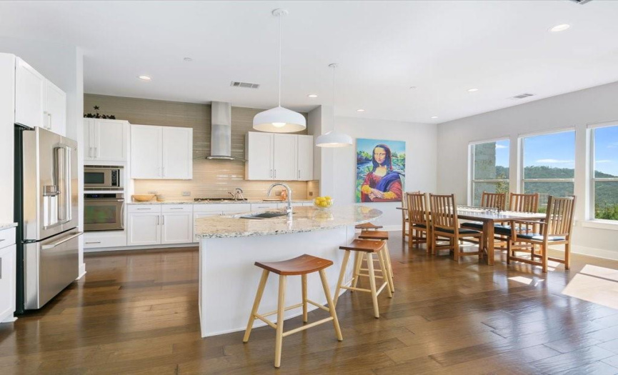 The kitchen features stainless appliances including a gas cooktop, and sleek stainless venthood, granite countertops and a full custom tile backsplash.