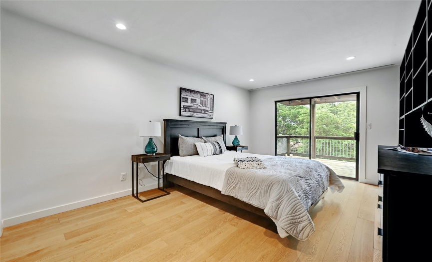 The third bedroom is located on the lower floor with wood flooring and access to another wood deck.