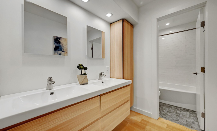 The third and fourth bedrooms share an updated guest bath with a modern dual vanity and a separate wet room with a tub/shower combo.