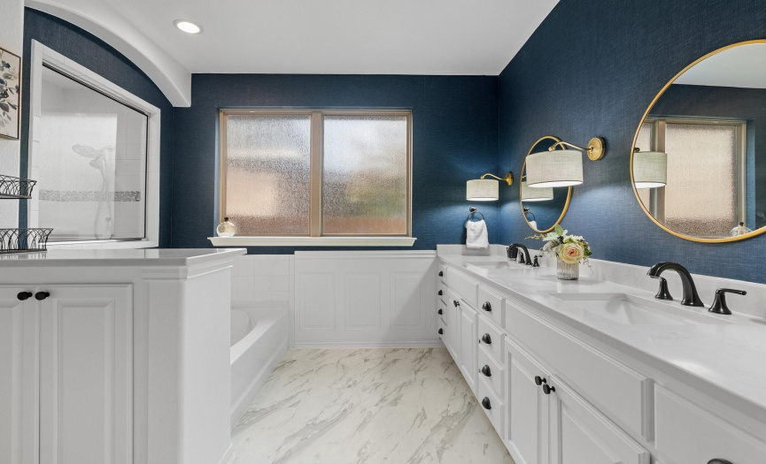 Marble style flooring blankets the ensuite bath, pairing beautifully with the pristine white cabinetry and quartz counters.