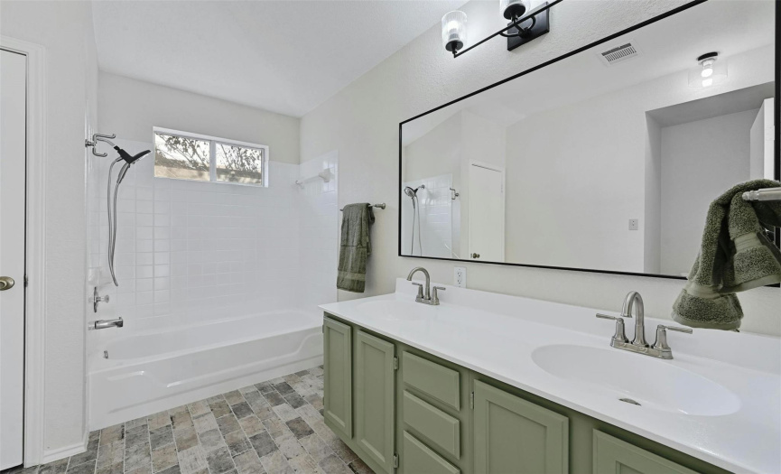 Primary bath with double vanity with updated faucets, mirror and lighting