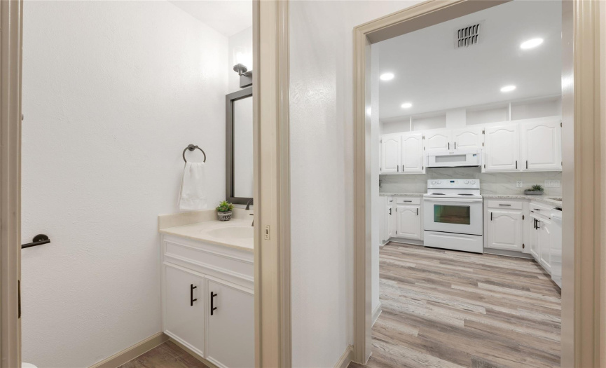 The guest bathroom is located next to the kitchen. The half bathroom offers a nice vanity, a new modern light fixture, new cabinet hardware and a modern framed mirror.