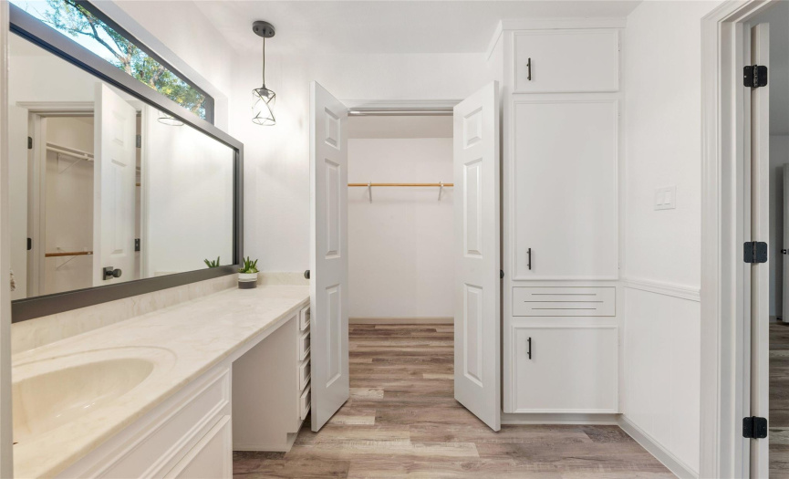 Through the French doors is a large walk-in closet with many clothing rods and additional shelving. There is a built-in linen cabinet with additional storage and a dirty clothes hamper.