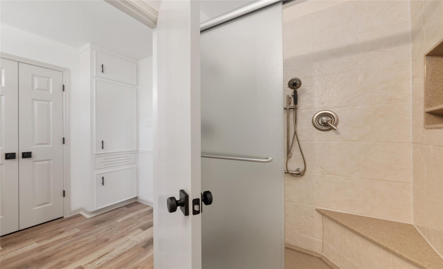 The walk-in shower was remodeled by Re-Bath for easy maintenance, has a nice size shower seat, shower niche, and privacy glass doors.