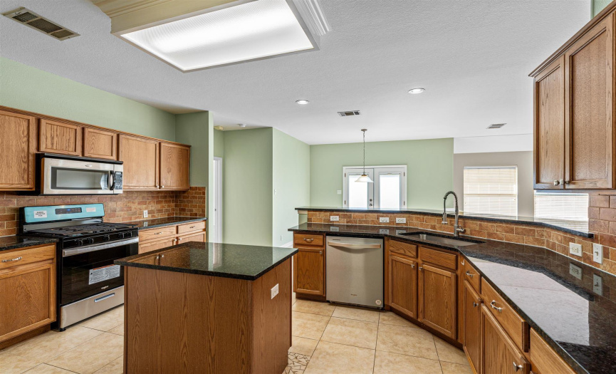 Spacious kitchen with center island, new granite installed in 2024 along with new dishwasher and gas range