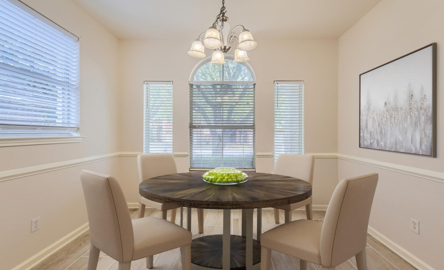Virtually Staged: The dining area is wrapped in windows with beautiful views of mature trees.