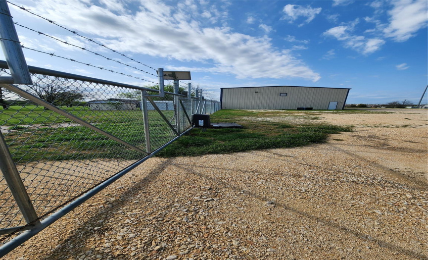 Back of property with two metal buildings in gated