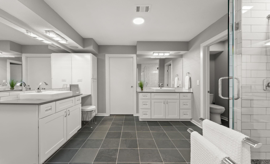Dual vanity primary bathroom with a walk in closet that features custom built in organization.