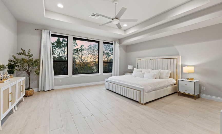 Enter the primary suite, with continued beautiful tiled floors, bathed in natural light. A pop-up ceiling adds height and grandeur to the room, offering a secluded haven for rest and rejuvenation.