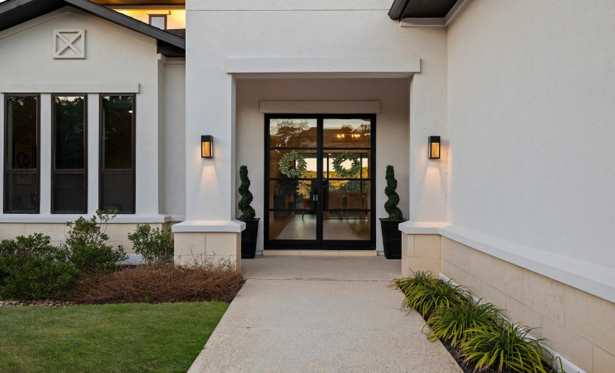Step into luxury through the elegant glass double doors of this stunning residence, where a covered porch offers a charming welcome and a serene space to unwind